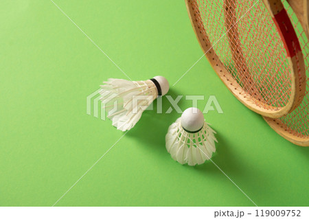 Two wooden badminton rackets and white feather badminton shuttlecocks on green background. View from above. Concept racket sport. Leisure games. 119009752