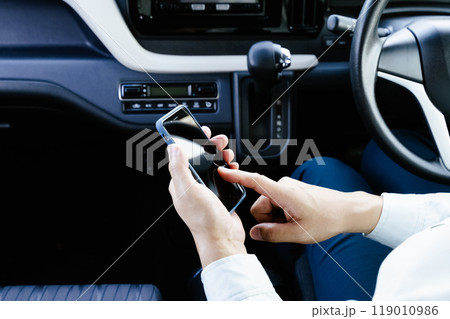 車内でスマホを操作する作業服の男性 車内でスマホを操作する作業服の男性 119010986