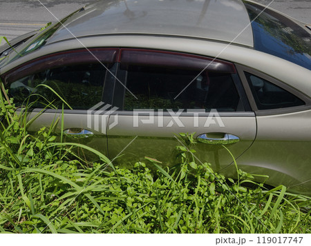 A silver car that has a broken tire and is covered with leaves 119017747