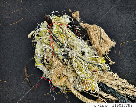 There is a pile of tightly wound rope and colorful yarn on a black surface There is a pile of tightly wound rope and colorful yarn on a black surface 119017798