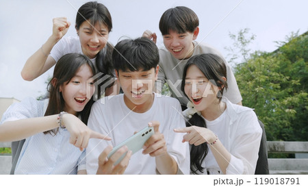 Happy young group of friends using phone and smiling together outdoor. 119018791