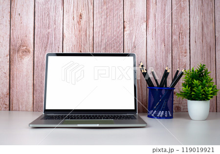 Laptop with blank screen on white table and office supplies on wooden background. Space for copying your text. Workspace and copy space. Desk with office supplies. 119019921