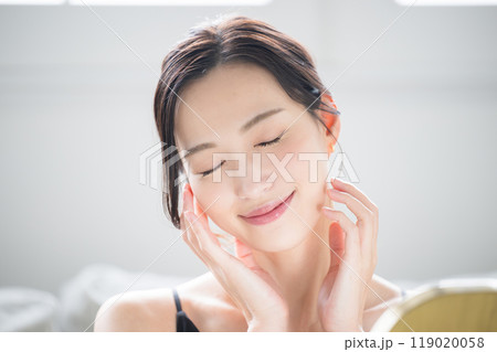 鏡をみながらスキンケアをする肌が美しい素肌感のある女性のクローズアップ目を閉じる 鏡をみながらスキンケアをする肌が美しい素肌感のある女性のクローズアップ目を閉じる 119020058
