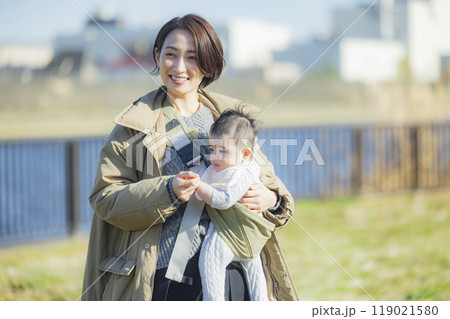 冬にお散歩する赤ちゃんを抱っこするお母さん　　 119021580