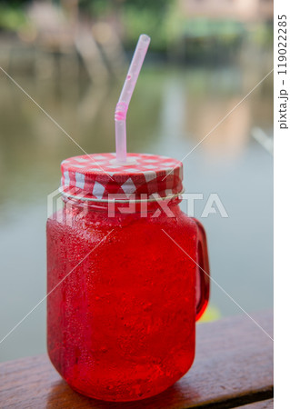 red drink juice on wooden table with riverside view red drink juice on wooden table with riverside view 119022285