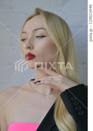 Close-up portrait of a blonde serious girl with different make-up on half of her face with her hand near her face on white background Close-up portrait of a blonde serious girl with different make-up on half of her face with her hand near her face on white background 119023046