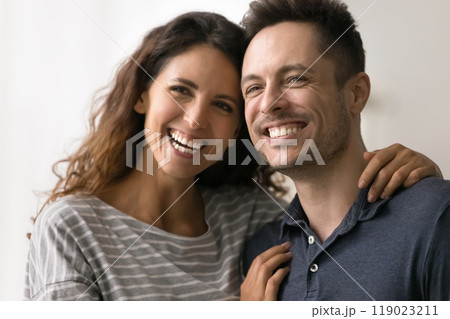 Cheerful young adult married couple standing close with heads touch 119023211