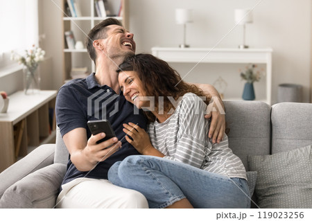 Cheerful young husband and wife in love relaxing with smartphone 119023256