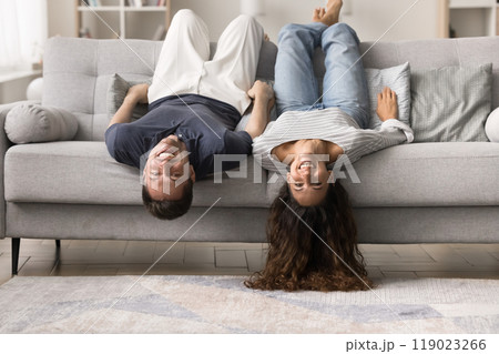 Happy carefree young couple resting upside down on comfortable couch Happy carefree young couple resting upside down on comfortable couch 119023266