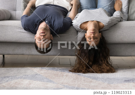 Sleeping young married couple lying upside down on home sofa 119023313