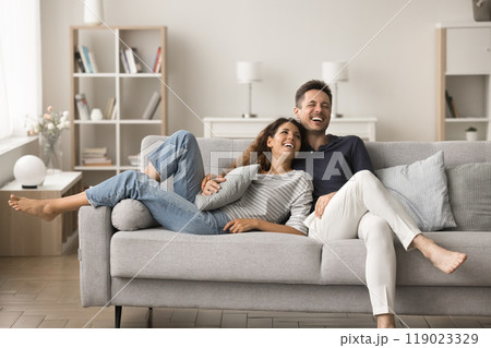 Positive happy young husband and wife relaxing on sofa Positive happy young husband and wife relaxing on sofa 119023329