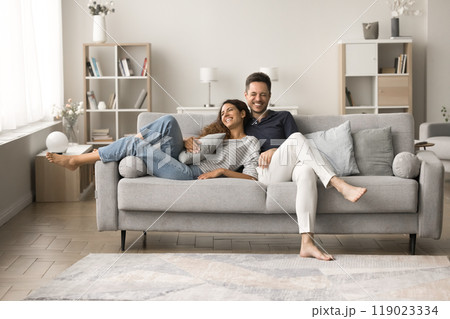 Positive happy young husband and wife relaxing on comfortable couch 119023334