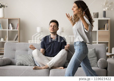 Calm silent husband meditating with closed eyes on home sofa 119023422