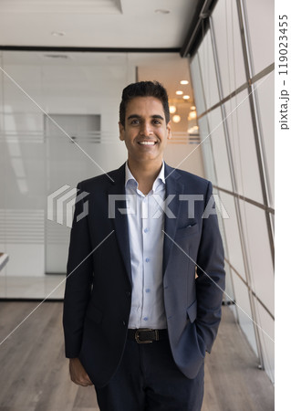 Positive middle aged Indian executive man standing in office Positive middle aged Indian executive man standing in office 119023455
