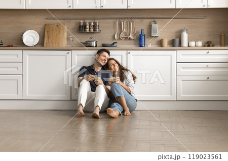 Happy couple of homeowners sitting on floor close together Happy couple of homeowners sitting on floor close together 119023561