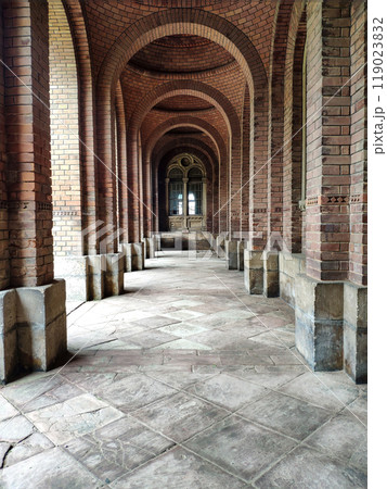 Old brick arch with tiles on the floor and closed doors. Elements of architectural decorations of buildings, arches and columns, door and window openings. On the streets in Catalonia, public places. 119023832