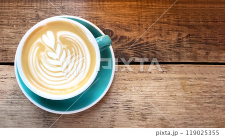 Coffee cup on a wooden table, top view, hot drink with foam in a rustic cafe setting. Brown beverage Coffee cup on a wooden table, top view, hot drink with foam in a rustic cafe setting. Brown beverage 119025355