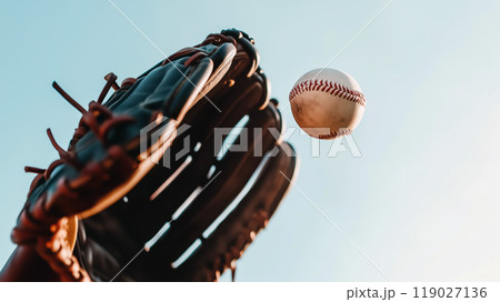 baseball is soaring through air towards black leather glove, capturing excitement of game. clear blue sky adds to vibrant atmosphere of this dynamic moment baseball is soaring through air towards black leather glove, capturing excitement of game. clear blue sky adds to vibrant atmosphere of this dynamic moment 119027136