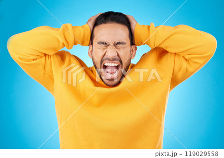 Angry, man and face with screaming in studio with burnout, anxiety and stress. Isolated, blue background and frustrated by problem with male person yelling and mental health from mistake and issue Angry, man and face with screaming in studio with burnout, anxiety and stress. Isolated, blue background and frustrated by problem with male person yelling and mental health from mistake and issue 119029558