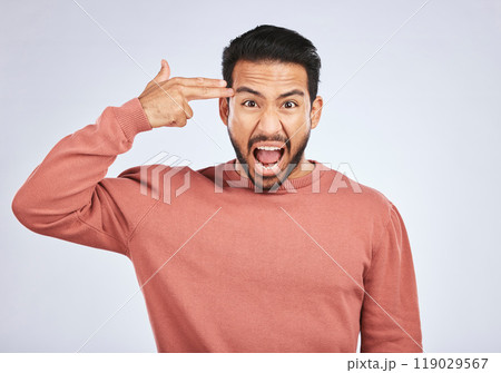 Portrait, angry and asian man with hand gun in studio for suicide, threat or shooting warning on grey background. Screaming, stress and face of male person with anxiety, self harm or bipolar crisis Portrait, angry and asian man with hand gun in studio for suicide, threat or shooting warning on grey background. Screaming, stress and face of male person with anxiety, self harm or bipolar crisis 119029567