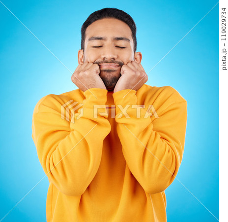 Man, shy and touching cheeks in studio isolated on a blue background. Peace, calm and person in love, relax for zen and meditation, content and satisfied with eyes closed, hands on face and wellness Man, shy and touching cheeks in studio isolated on a blue background. Peace, calm and person in love, relax for zen and meditation, content and satisfied with eyes closed, hands on face and wellness 119029734