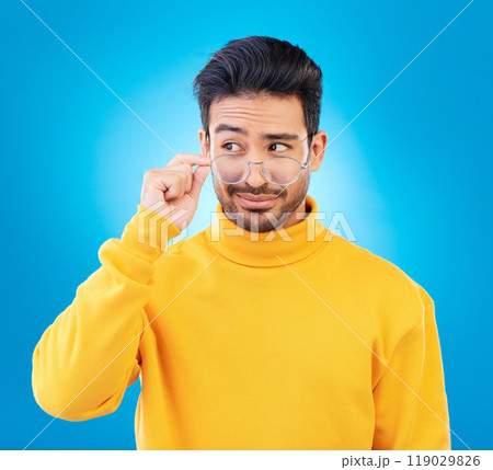 Thinking, glasses and Asian man with ideas, decision and emoji against a blue studio background. Male person, model and guy with eyewear, opportunity or choice with solution, focus or problem solving 119029826