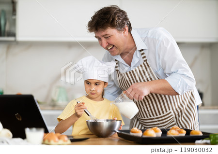 Father and daughter preparing muffins in kitchen Father and daughter preparing muffins in kitchen 119030032