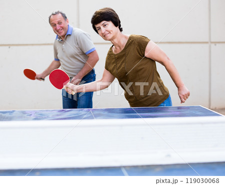 Mature man and woman playing table tennis 119030068