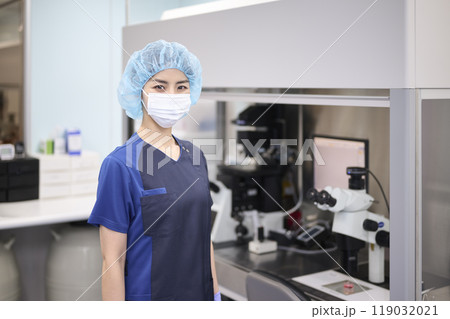 培養室で顕微鏡を使うマスク姿の若い女性培養士 培養室で顕微鏡を使うマスク姿の若い女性培養士 119032021