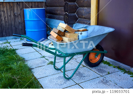 Wheelbarrow with Firewood and Tools in a Backyard 119033701