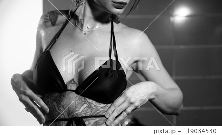 Sexy woman fashion model takes a shower in a swimsuit, posing for the camera. Monochrome photography. 119034530