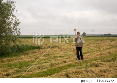 A male surveyor works with a GNSS receiver, from the back 119035372