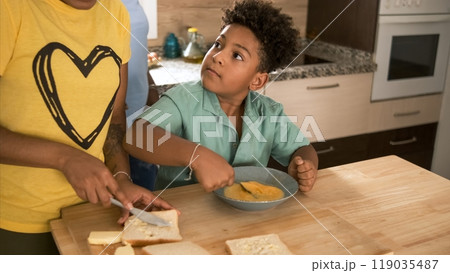 Boy looking at sister while whisking egg yolk as they prepare breakfast 119035487