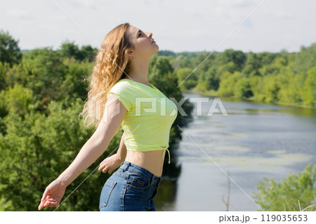 A woman rests in nature with her arms outstretched, the concept of emotional balance 119035653