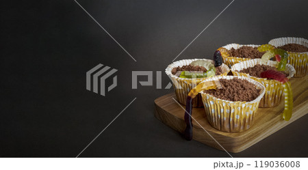 Cupcakes with edible jelly worms for Halloween celebration stand ready to be eaten, copy space Cupcakes with edible jelly worms for Halloween celebration stand ready to be eaten, copy space 119036008