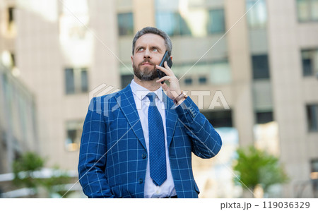 Hispanic business man with phone at office building. Businessman using phone. Man phone conversation in city. Businessman talking on phone. Businessman employer in front office. Social network Hispanic business man with phone at office building. Businessman using phone. Man phone conversation in city. Businessman talking on phone. Businessman employer in front office. Social network 119036329