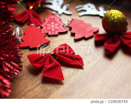 A red bow, wooden Christmas trees, deer and balloons for decoration for New Year and Christmas lie on the background of a wooden surface. Seasonal holidays and festive decorations A red bow, wooden Christmas trees, deer and balloons for decoration for New Year and Christmas lie on the background of a wooden surface. Seasonal holidays and festive decorations 119036743