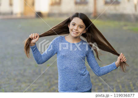 Teen girl with long hair outdoor. Autumn fashion girl. Trendy and stylish teenager girl smiling. Fall fashion style for teen. Complete outfit style. Girl portrait in casual sweater. Long strong hair 119036877