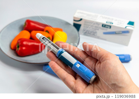 Hands holding Ozempic Insulin injection pen for diabetics and weight loss 119036988