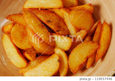 Golden potato wedges, perfectly seasoned and golden, are artfully arranged in a charming bowl 119037446