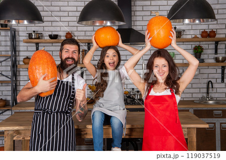 cheerful parents with kid girl cook pumpkin. father mother and child in kitchen. 119037519