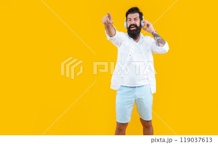 bearded man listening music in headphones isolated on yellow, copy space. man listening music bearded man listening music in headphones isolated on yellow, copy space. man listening music 119037613