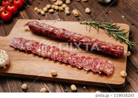 Sliced gourmet smoked salami on a wooden board with herbs, perfect for charcuterie boards and snacks 119038285