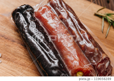 Assorted vacuum-packed salami with nuts and spices on board, charcuterie and gourmet dishes 119038289