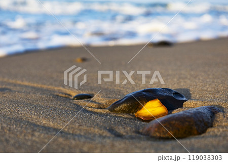 A beautiful piece of amber lies on the warm sand of the beach A beautiful piece of amber lies on the warm sand of the beach 119038303