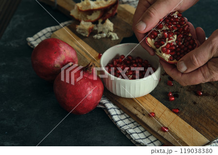 a man breaks open a ripe red pomegranate 119038380