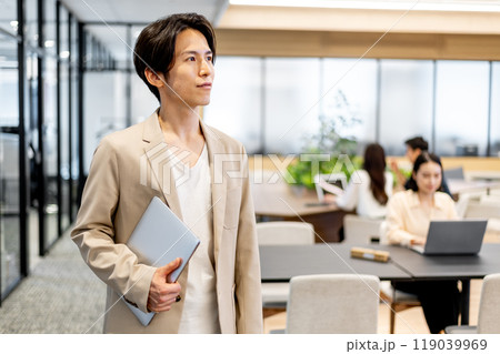 パソコンを小脇に抱えて斜め左方向を向いているビジネスマン パソコンを小脇に抱えて斜め左方向を向いているビジネスマン 119039969