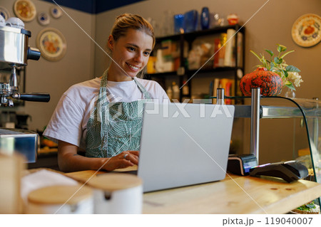 A skilled barista works on a laptop in a cozy coffee shop on a lovely afternoon A skilled barista works on a laptop in a cozy coffee shop on a lovely afternoon 119040007