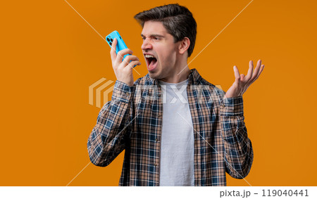 Angry handsome man quarreling, screaming talking on mobile phone. Guy in stress Angry handsome man quarreling, screaming talking on mobile phone. Guy in stress 119040441