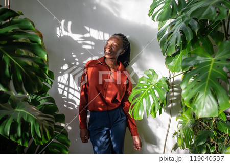 Relaxed African American woman stand in home garden enjoying houseplants. Mental health, slow life 119040537